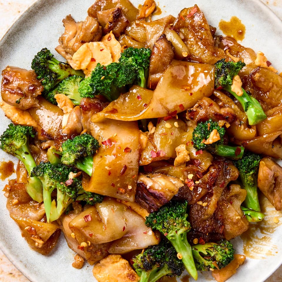 Close-up of Thai Taste's Pad See Ew with wide noodles, chicken, broccoli, and chili flakes.